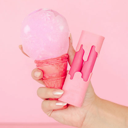 Hand holding a pink ice cream cone with a pink scoop against a pink background